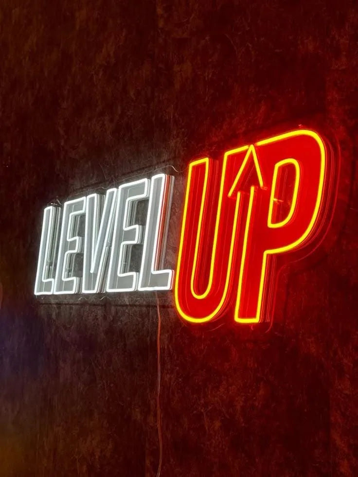 Beleuchtetes LED-Neonschild „LEVEL UP“ in Weiß und Rot an einer Wand