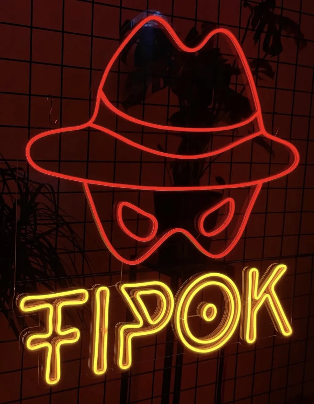 Neonschild TIPOK mit rotem Hut und gelbem Schriftzug